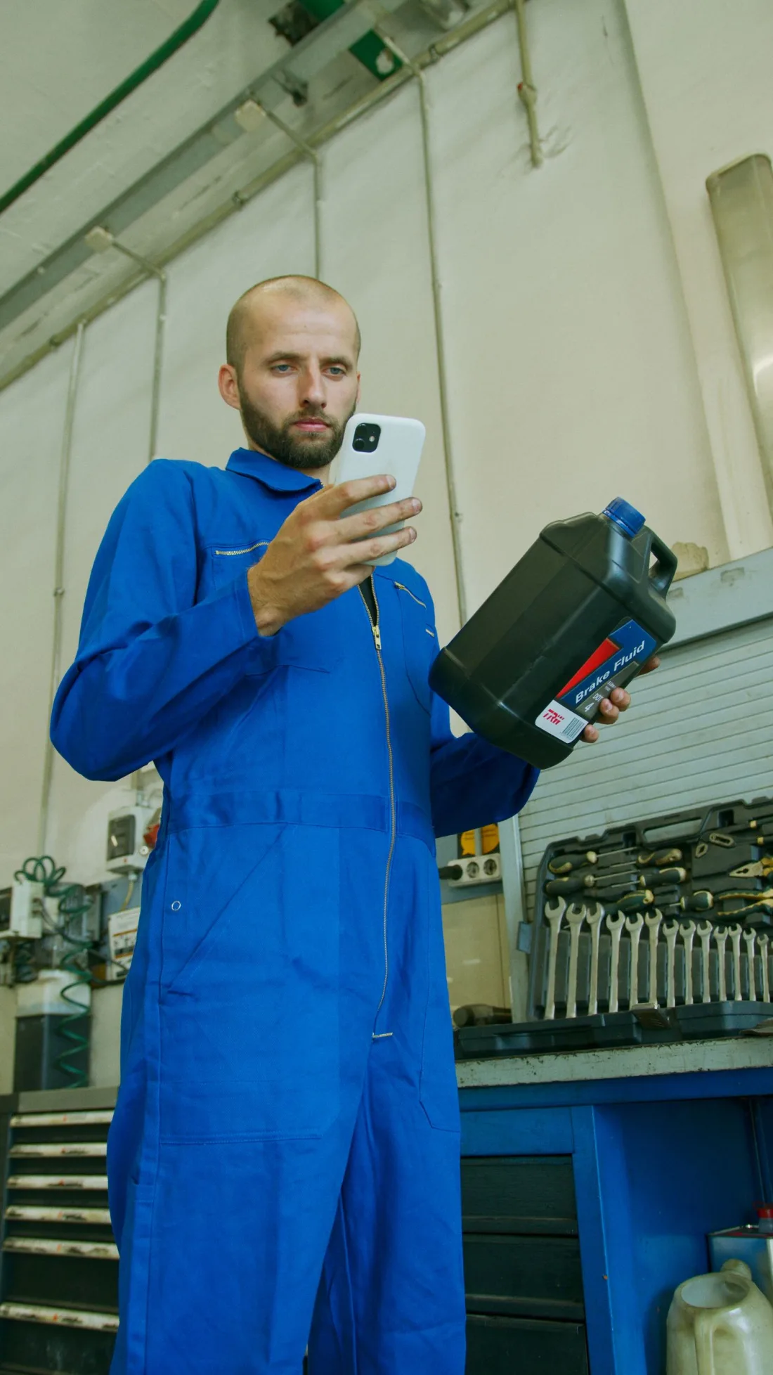 Monteur in Arbeitskleidung mit dem Handy in der Hand